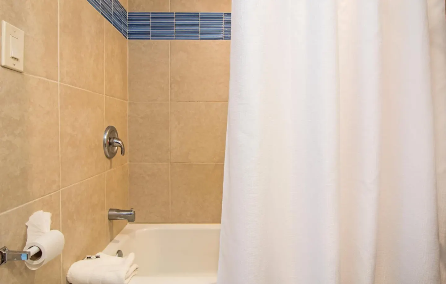 Standard Room bathroom tub with white shower curtain at Windward Passage Hotel.