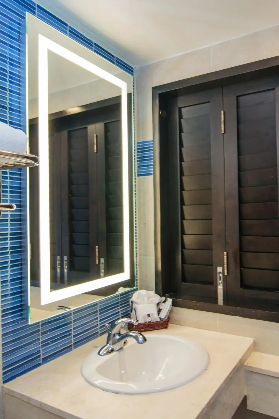 Standard Room bathroom vanity with lit mirror and shutters at Windward Passage Hotel.