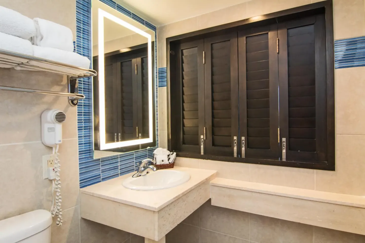 Standard Room bathroom vanity with towels, hair dryer, and shutters at Windward Passage Hotel.
