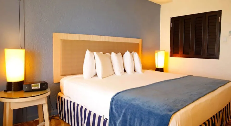 Standard Room king bed with blue throw and bedside lamps at Windward Passage Hotel.