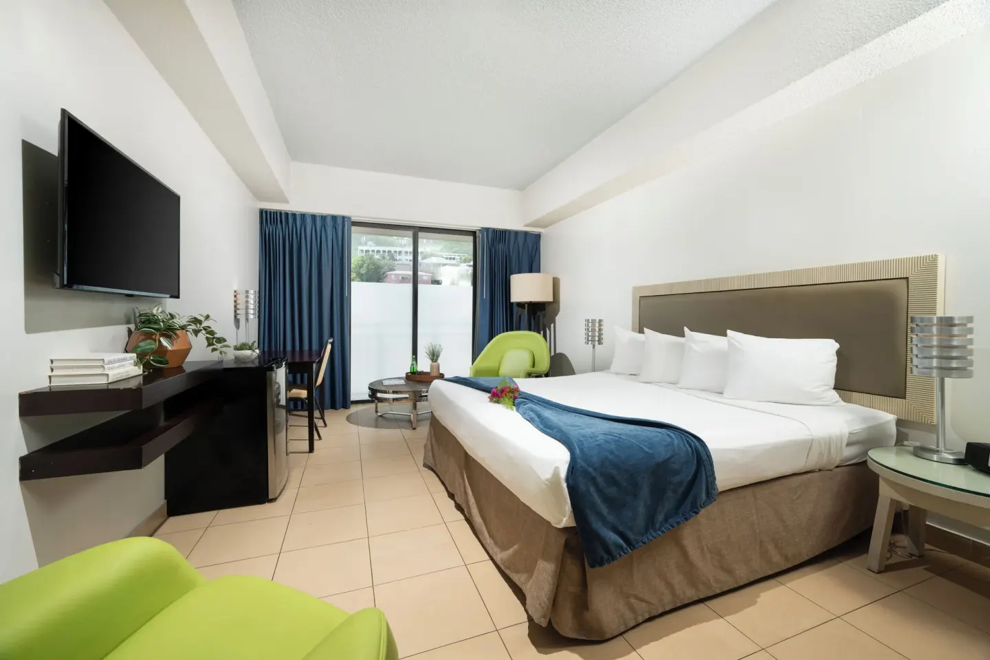 Standard room with king bed, TV wall, desk and seating area at Windward Passage Hotel.