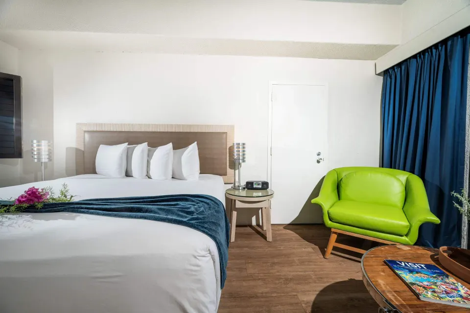 Superior Ocean View room with king bed, green chair, and blue curtains at Windward Passage Hotel.