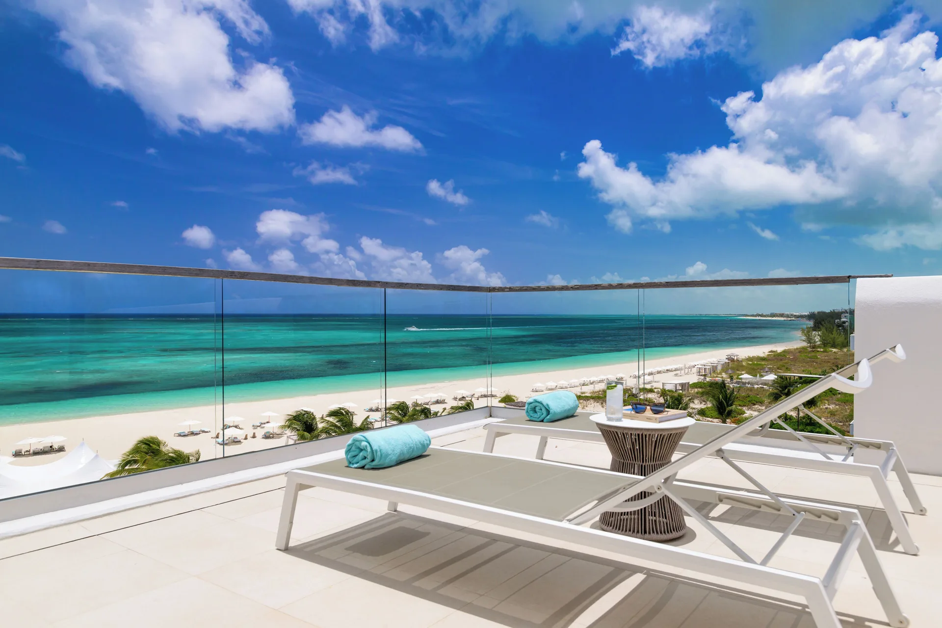 Beach-view balcony with loungers and glass railing at Wymara Resort and Villas.