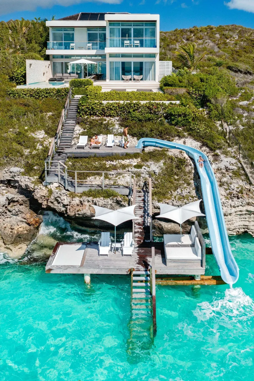 Cliffside villa with water slide, dock, and overwater loungers at Wymara Resort and Villas.