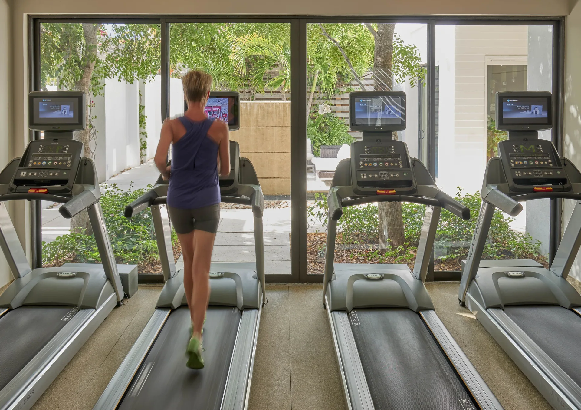 Guest running on a treadmill in the fitness room at Wymara Resort and Villas.