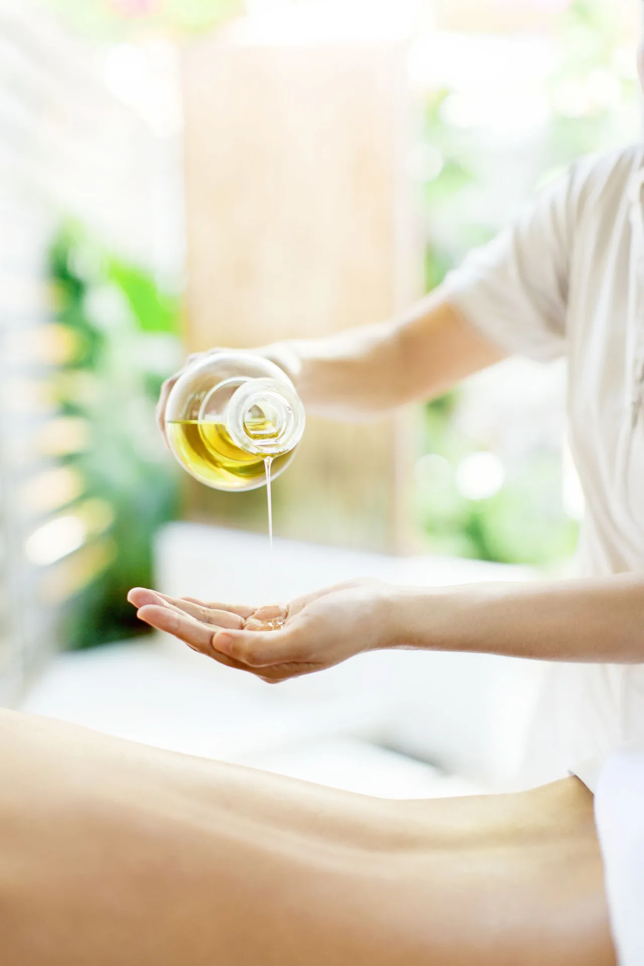 Spa therapist pouring massage oil into a hand during a treatment at Wymara Resort and Villas.