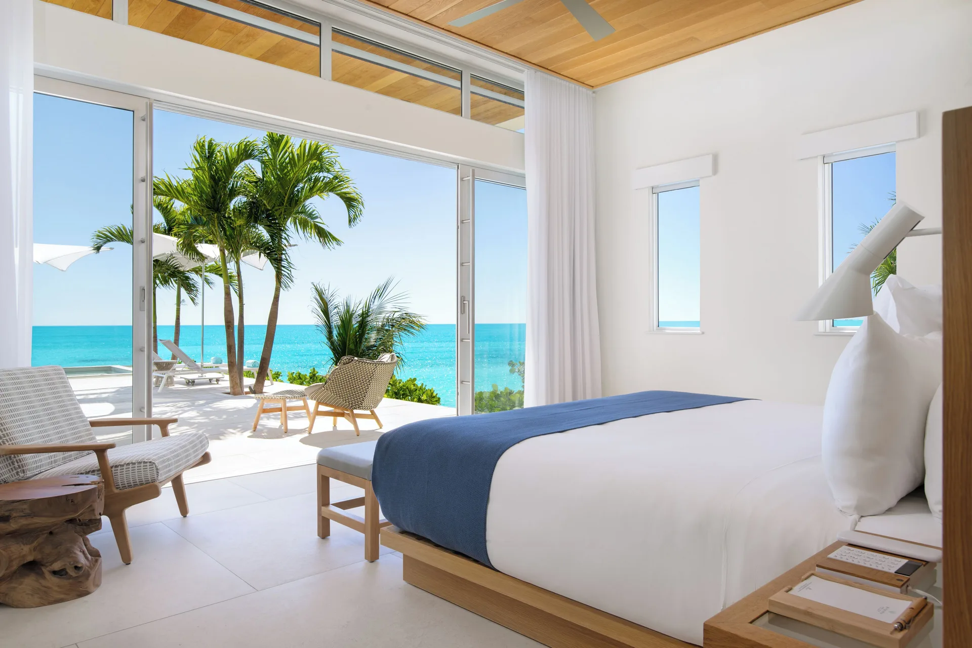 Oceanfront king bedroom with palm-shaded terrace at Wymara Resort and Villas.