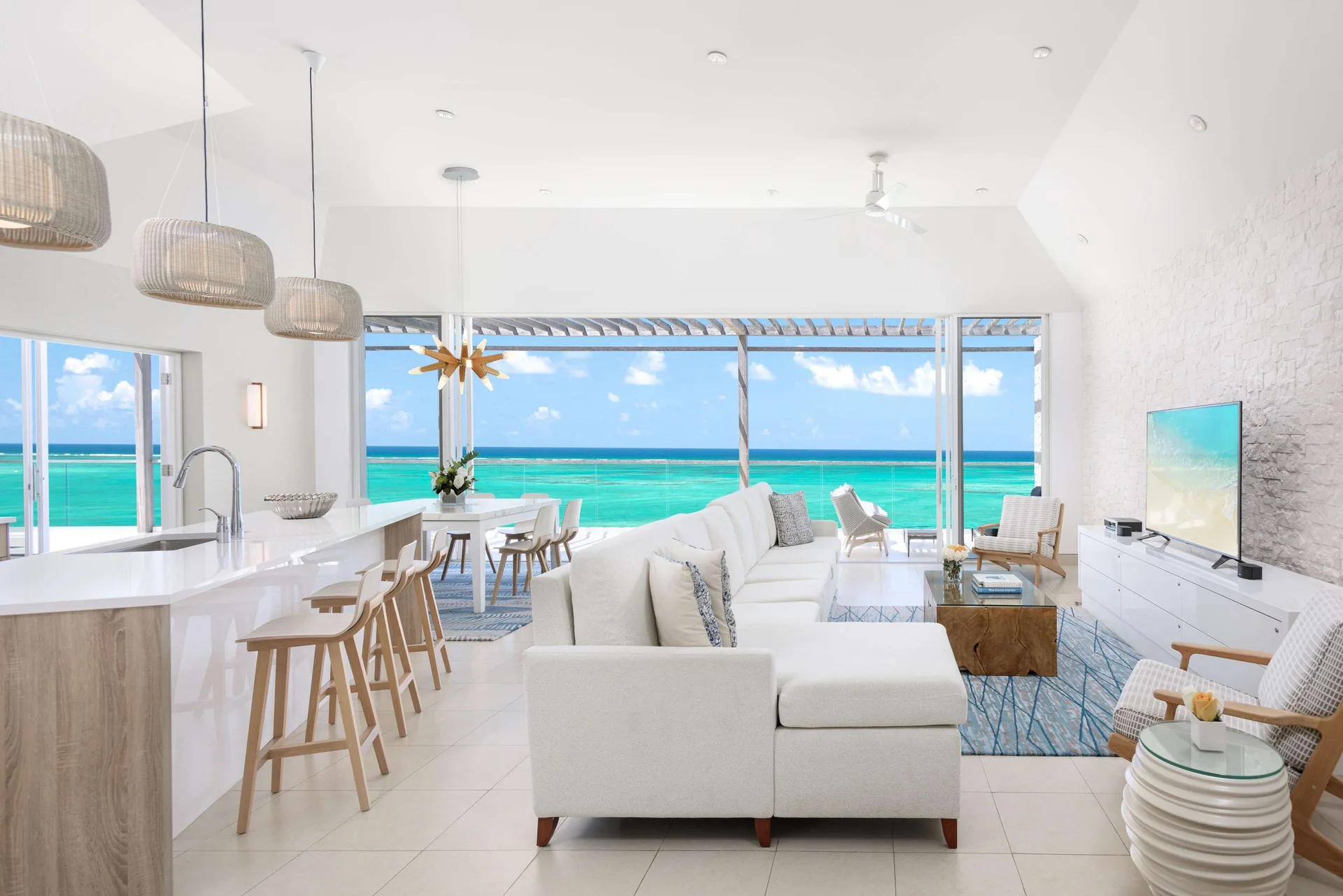 Open-plan oceanfront living room and kitchen with bar seating at Wymara Resort and Villas.