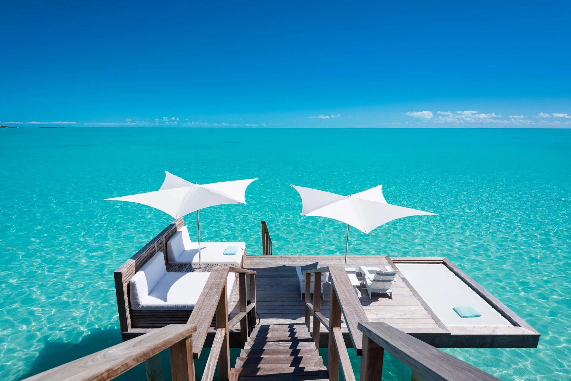 Overwater sun deck with white umbrellas at Wymara Resort and Villas.