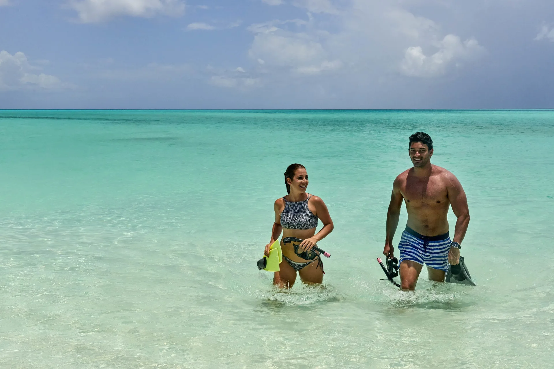 Two snorkelers walking through clear turquoise water at Wymara Resort and Villas.