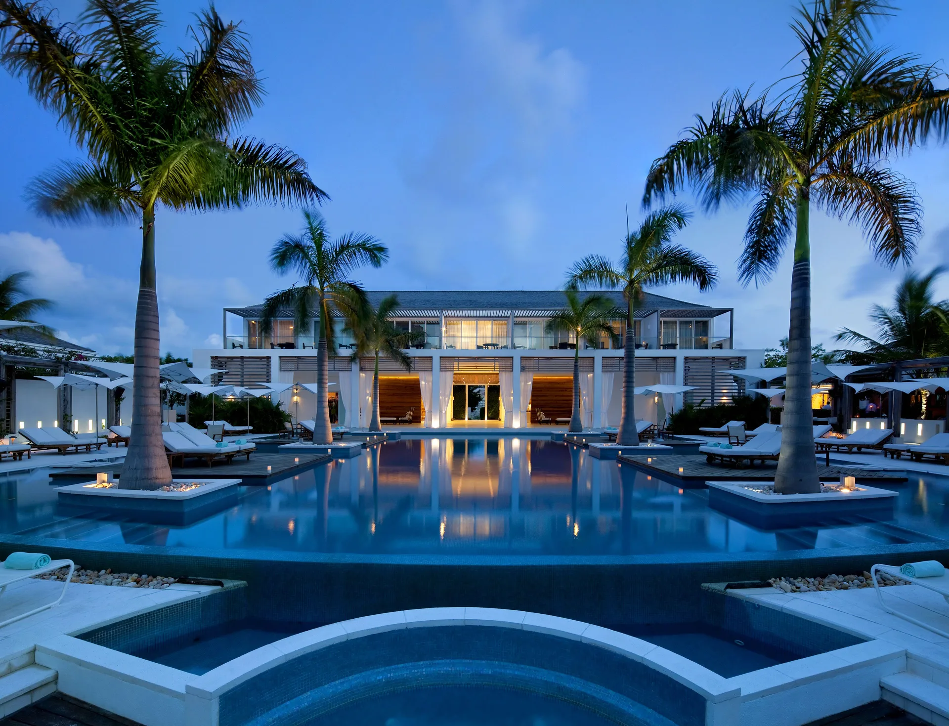 Symmetrical twilight pool view with palms and lit terraces at Wymara Resort and Villas.