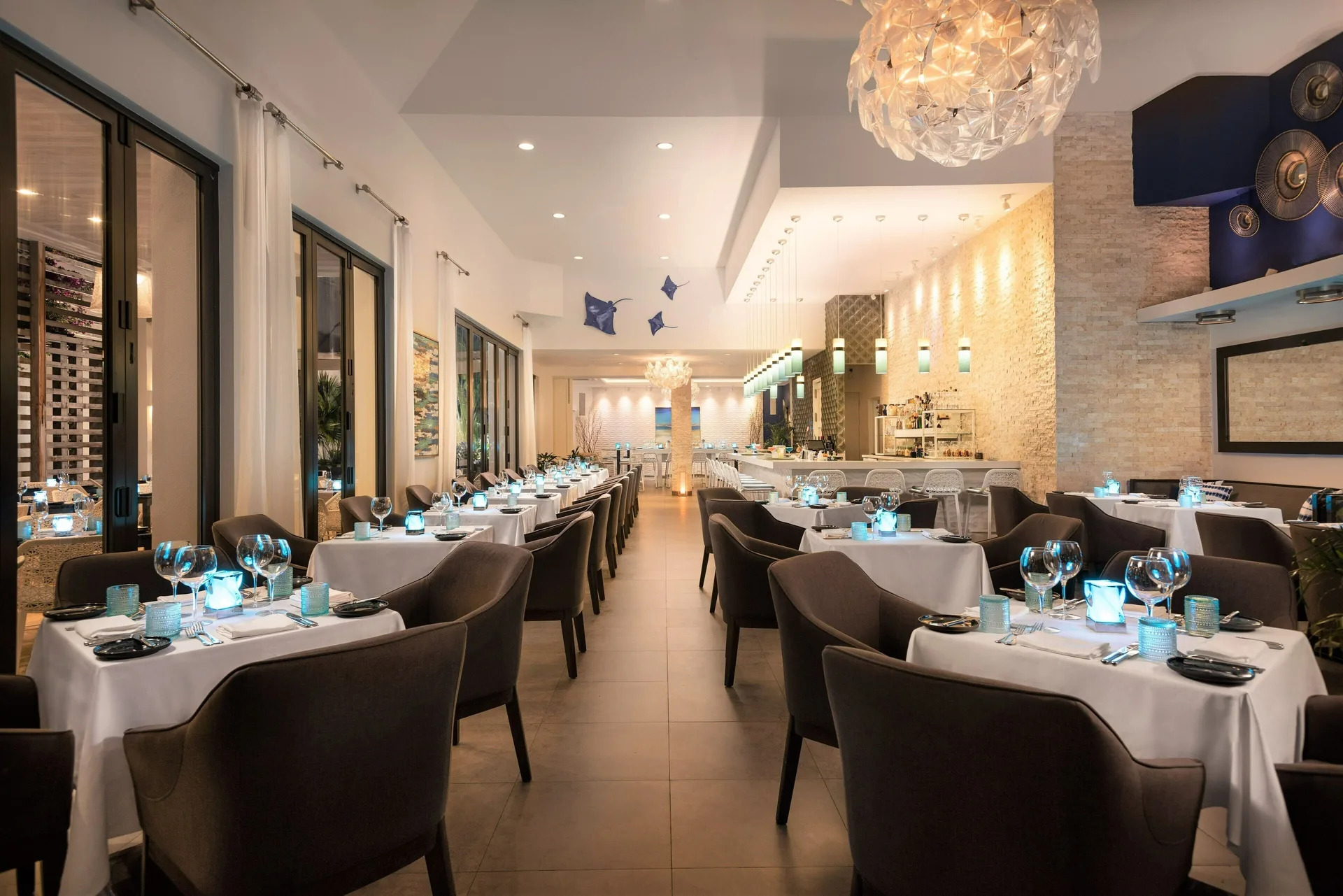 Elegant indoor dining room with set tables and blue accent lighting at Wymara Resort and Villas.