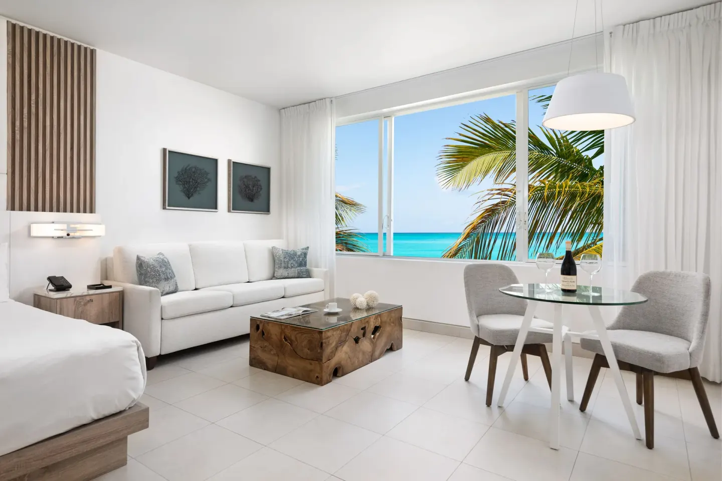 Grand Suite oceanfront living area with bed, sofa, dining table and sea view at Wymara Resort and Villas.