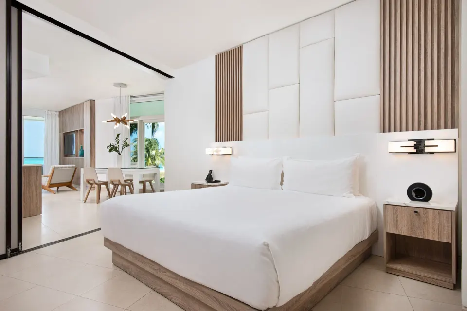 Oceanfront one-bedroom suite king bed with living area beyond at Wymara Resort and Villas.