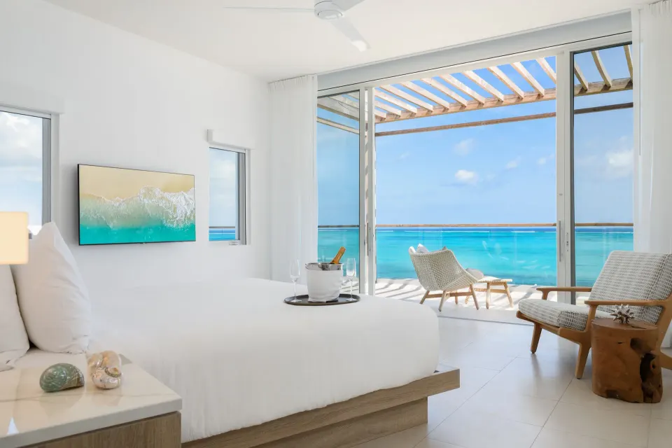 Oceanfront penthouse suite bedroom with terrace and turquoise water at Wymara Resort and Villas.