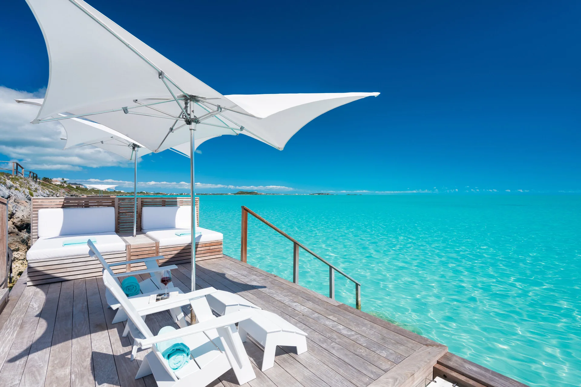 Waterfront deck with loungers and white umbrellas at Wymara Resort and Villas.
