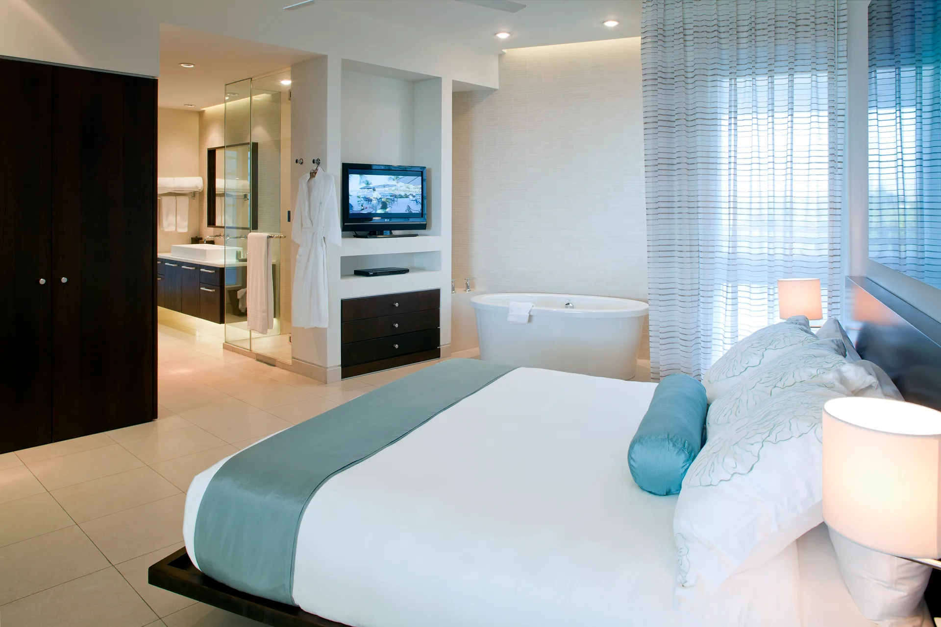 Villa bedroom with bed, soaking tub and open bath area at Wymara Resort and Villas.