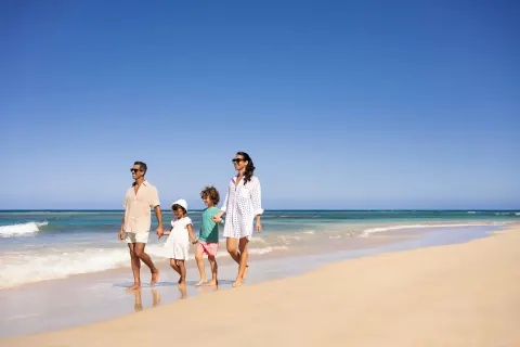 Family walking along the sandy shoreline at Wyndham Alltra Punta Cana.