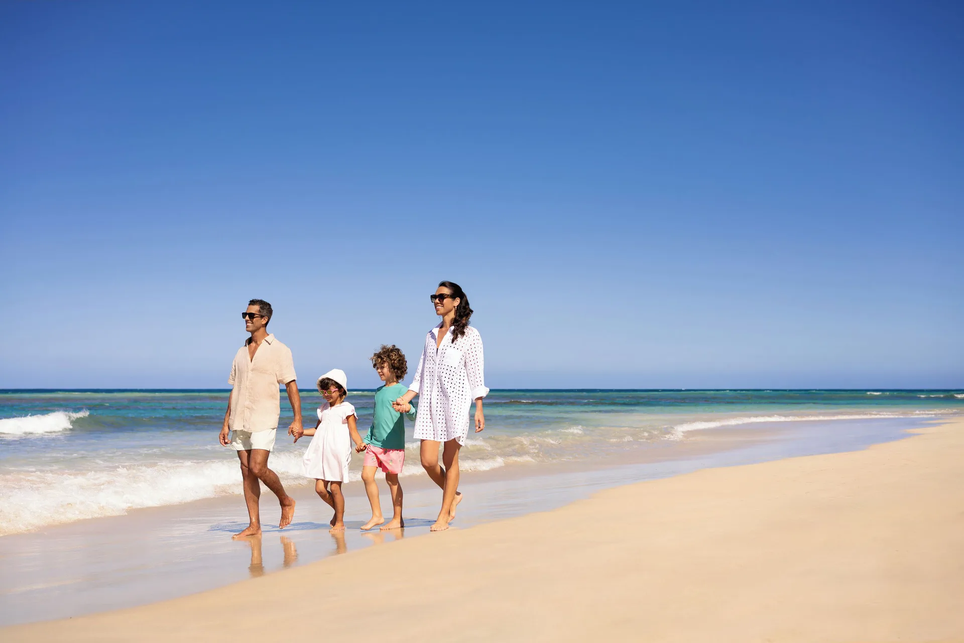 Family walking along the sandy shoreline at Wyndham Alltra Punta Cana.