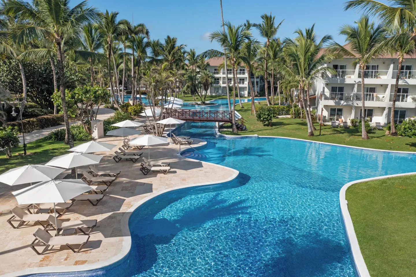 Palm-lined pool with loungers and guest buildings at Wyndham Alltra Punta Cana.