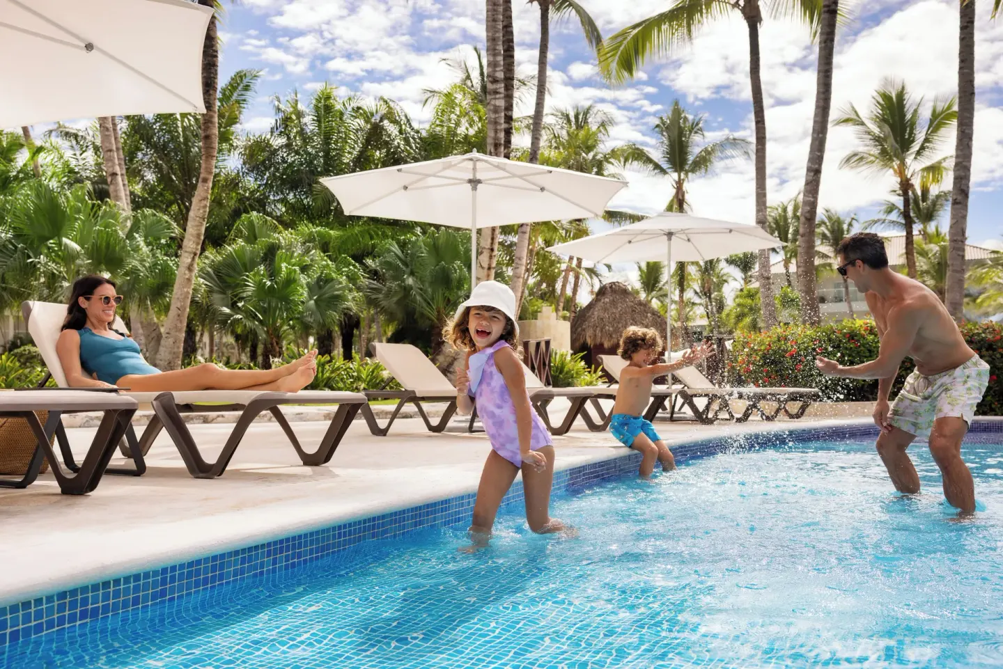Children playing in the pool beside loungers and palms at Wyndham Alltra Punta Cana.