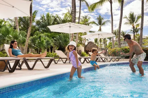Children playing in the pool beside loungers and palms at Wyndham Alltra Punta Cana.