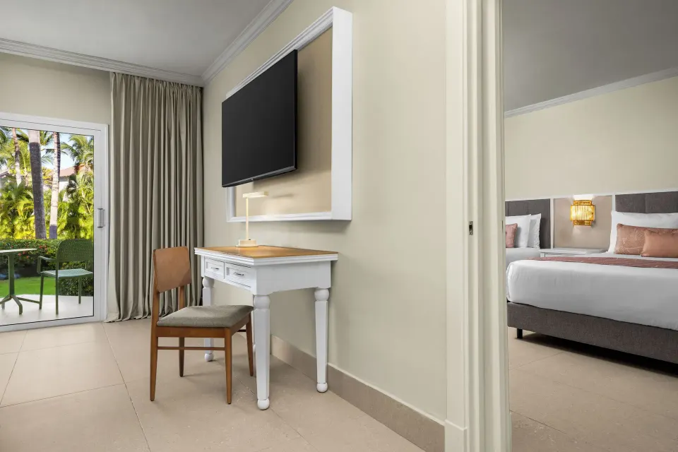 Junior Suite Multiple Beds Tropical View desk and balcony doors at Wyndham Alltra Punta Cana.