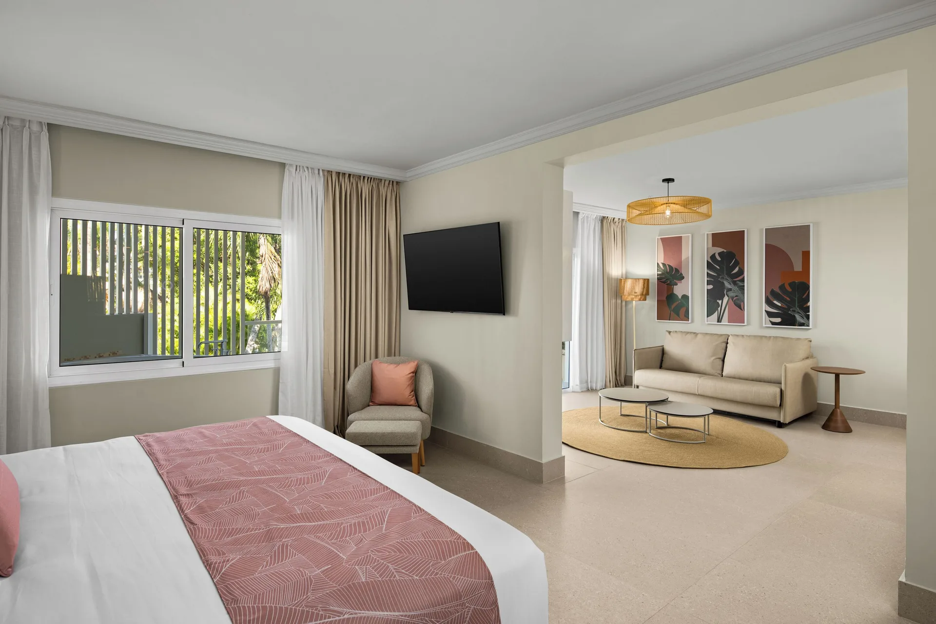 Junior suite with bed, sofa bed and tropical greenery at Wyndham Alltra Punta Cana.