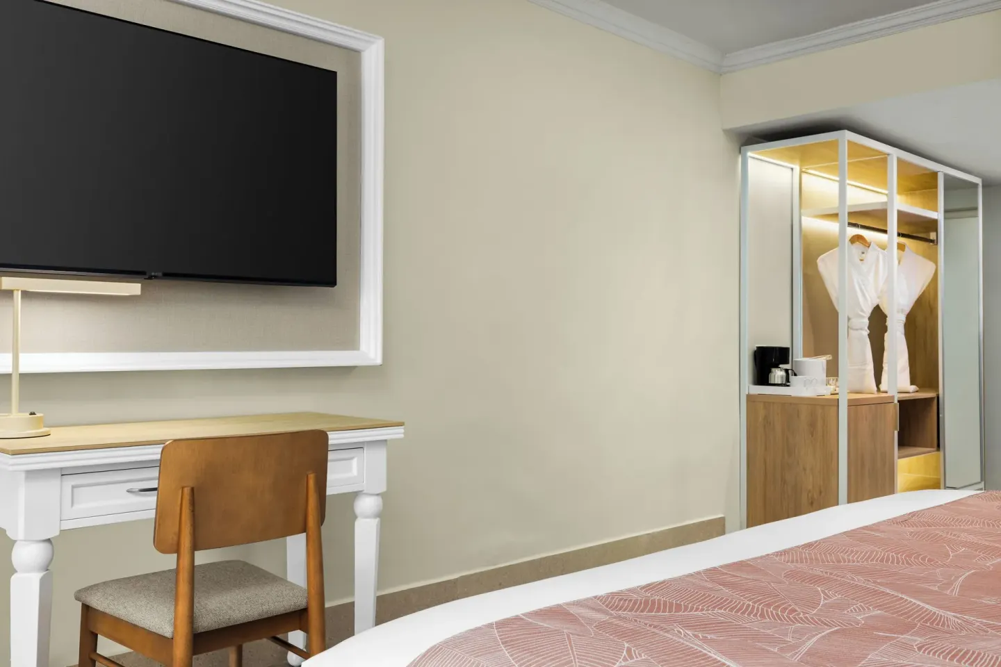 Standard tropical view room desk, TV, closet, and robe at Wyndham Alltra Punta Cana.