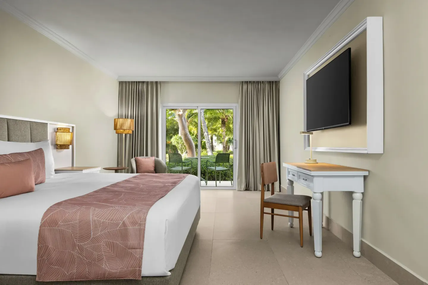 Standard tropical view room with a king bed, desk, TV, and patio at Wyndham Alltra Punta Cana.