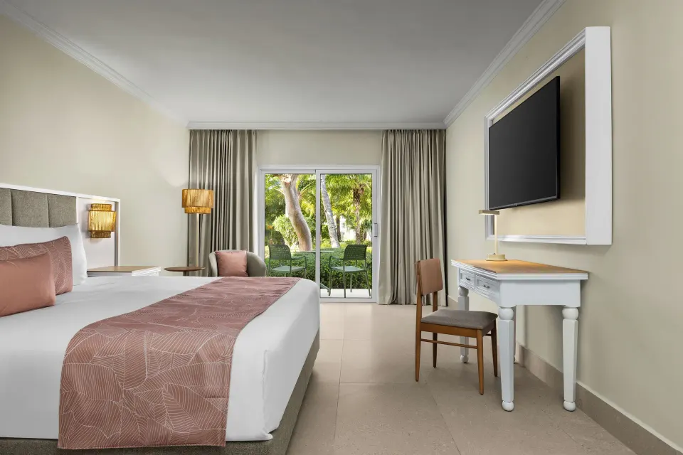 Standard tropical view room with a king bed, desk, TV, and patio at Wyndham Alltra Punta Cana.