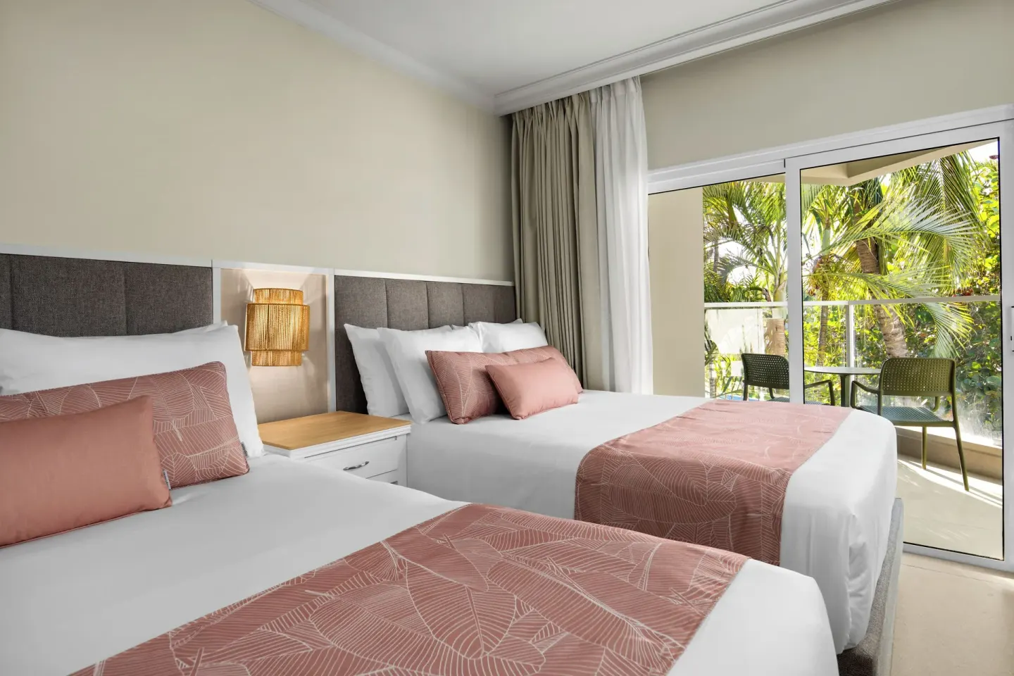 Standard tropical view room with two beds beside balcony doors at Wyndham Alltra Punta Cana.