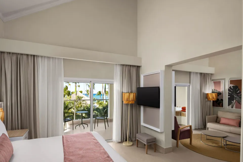 Suite bedroom and sitting area with balcony ocean glimpse at Wyndham Alltra Punta Cana.