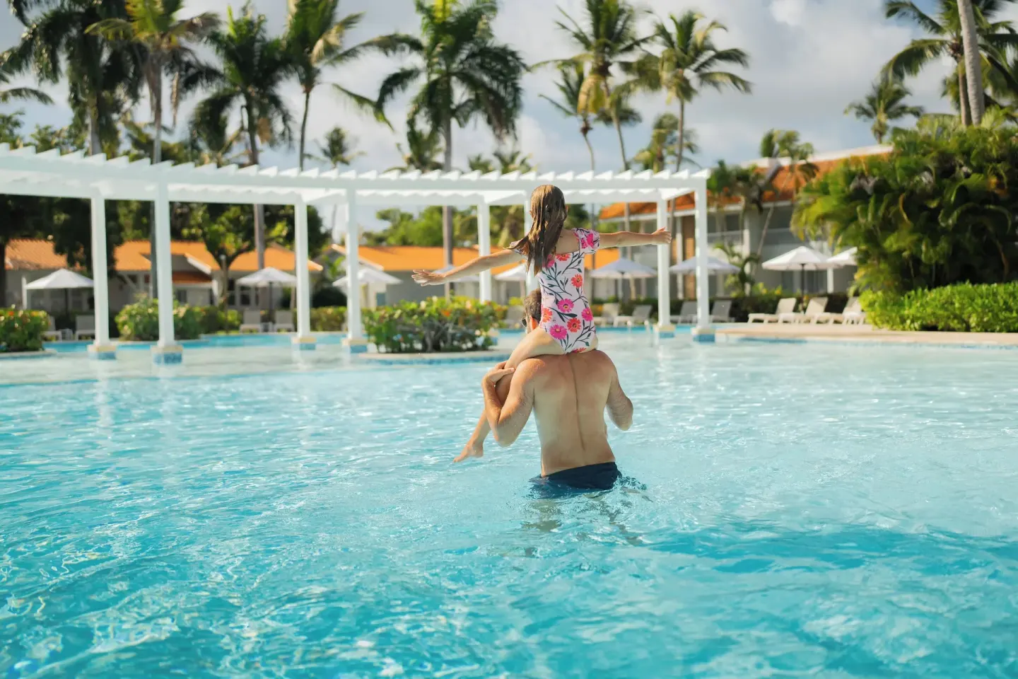 Adult carrying a child through the pool at Wyndham Alltra Samana Resort.