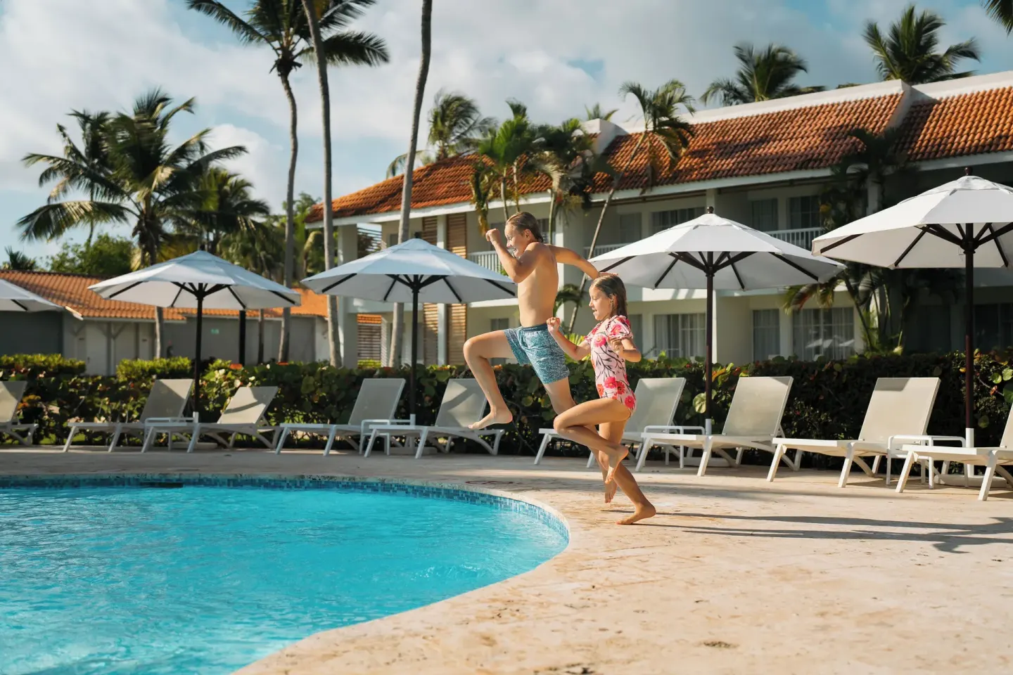 Two children jumping into the pool at Wyndham Alltra Samana Resort.