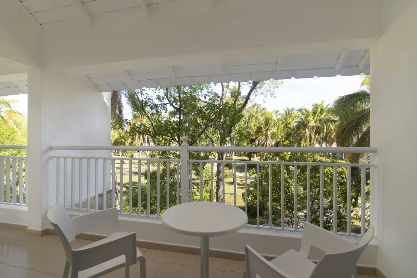 Covered balcony with white chairs and garden views at Wyndham Alltra Samana Resort.