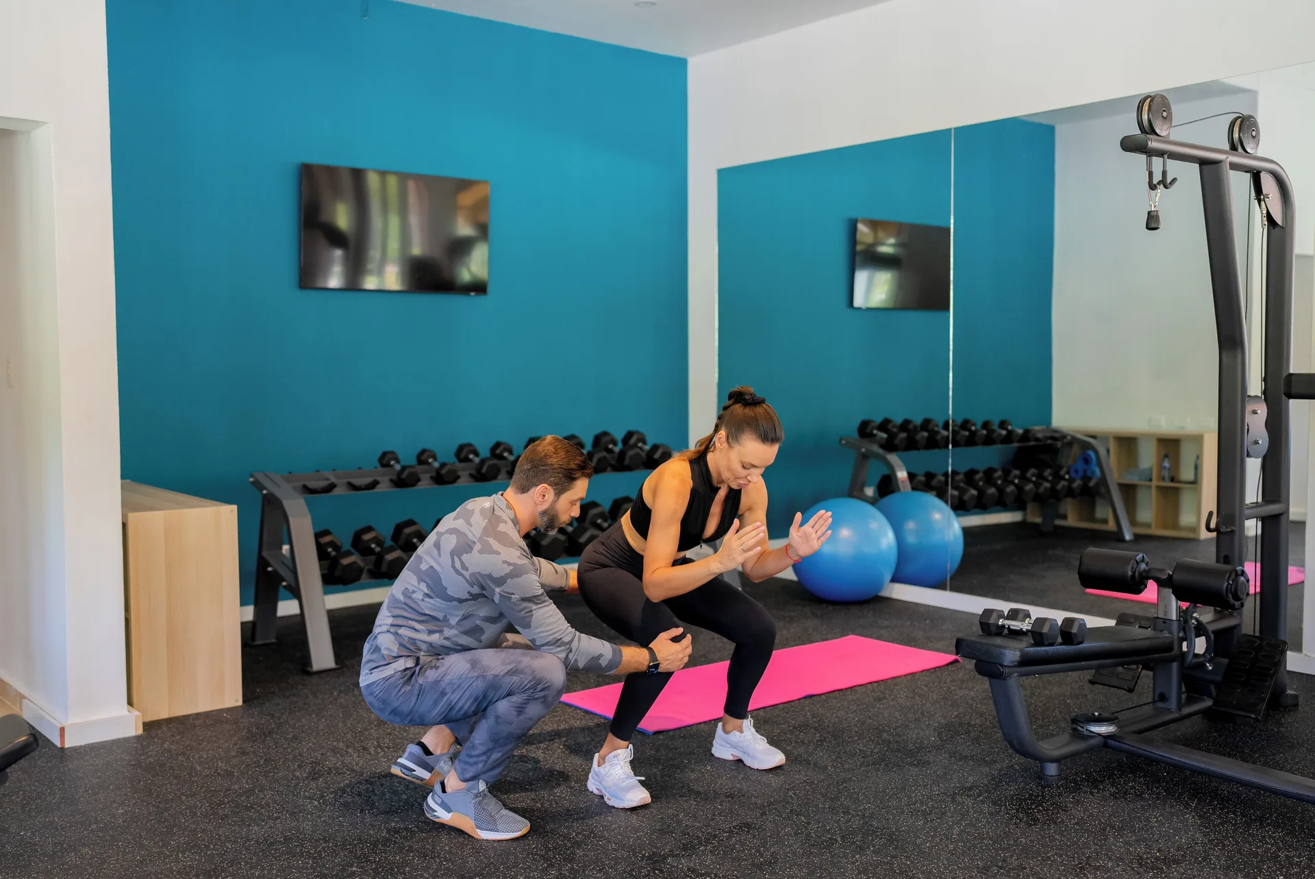 Trainer assisting a guest with a workout in the gym at Wyndham Alltra Samana Resort.
