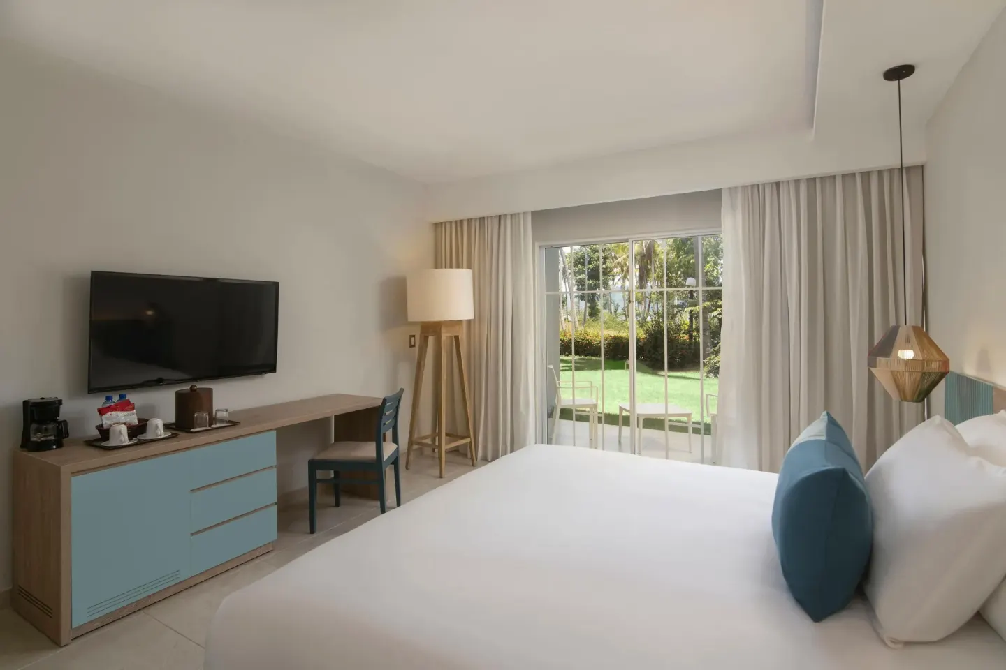 King-bed guest room with garden-facing sliding doors at Wyndham Alltra Samana Resort.