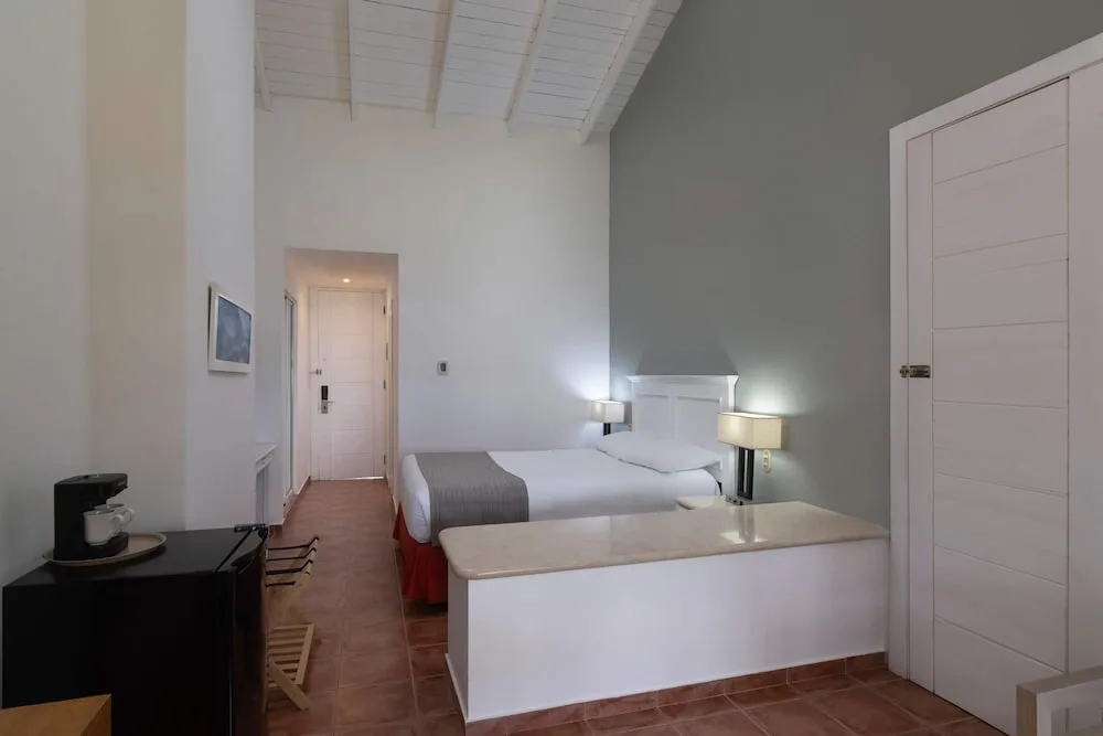 King bed guest room with high ceiling and wardrobe at Wyndham Alltra Samana Resort.