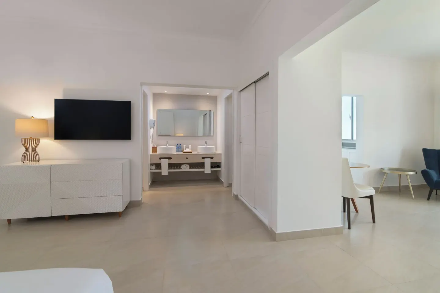 Guest room living area with TV, bathroom vanity, and seating at Wyndham Alltra Samana Resort.