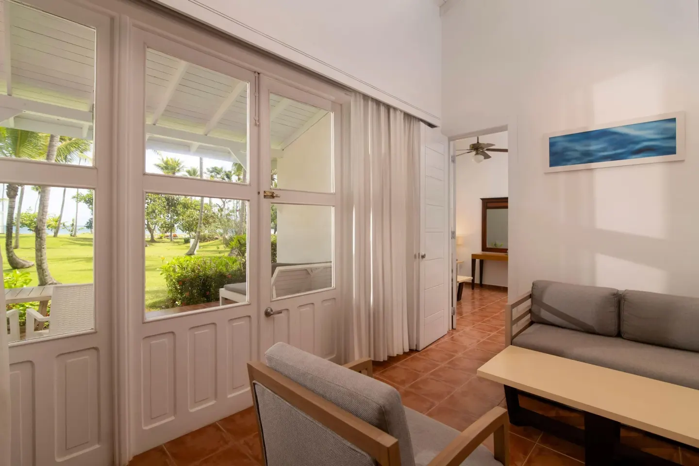 Guest room sitting area with garden-facing glass doors at Wyndham Alltra Samana Resort.