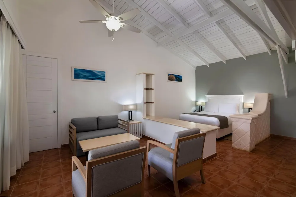 King guest room with sofa seating and high white ceiling at Wyndham Alltra Samana Resort.