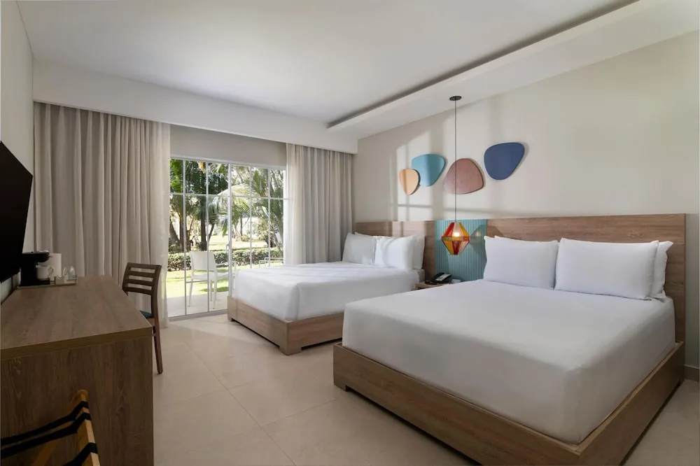 Double-bed guest room with sliding doors and garden view at Wyndham Alltra Samana Resort.
