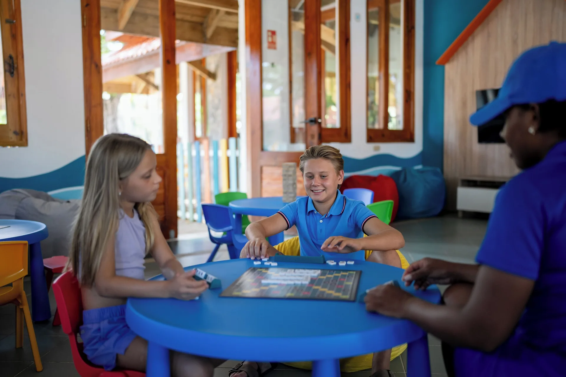 Children play a board game with a staff member at Wyndham Alltra Samana Resort.