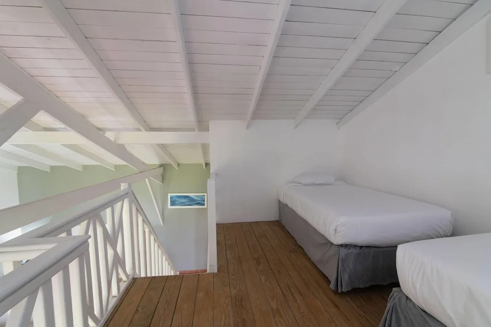 Loft sleeping area with two beds and white railing at Wyndham Alltra Samana Resort.