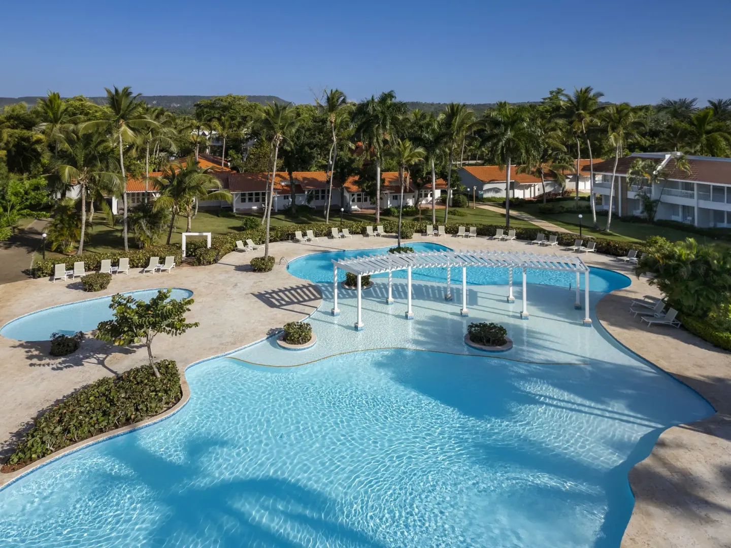 Large pool with white pergola and palm trees at Wyndham Alltra Samana Resort.