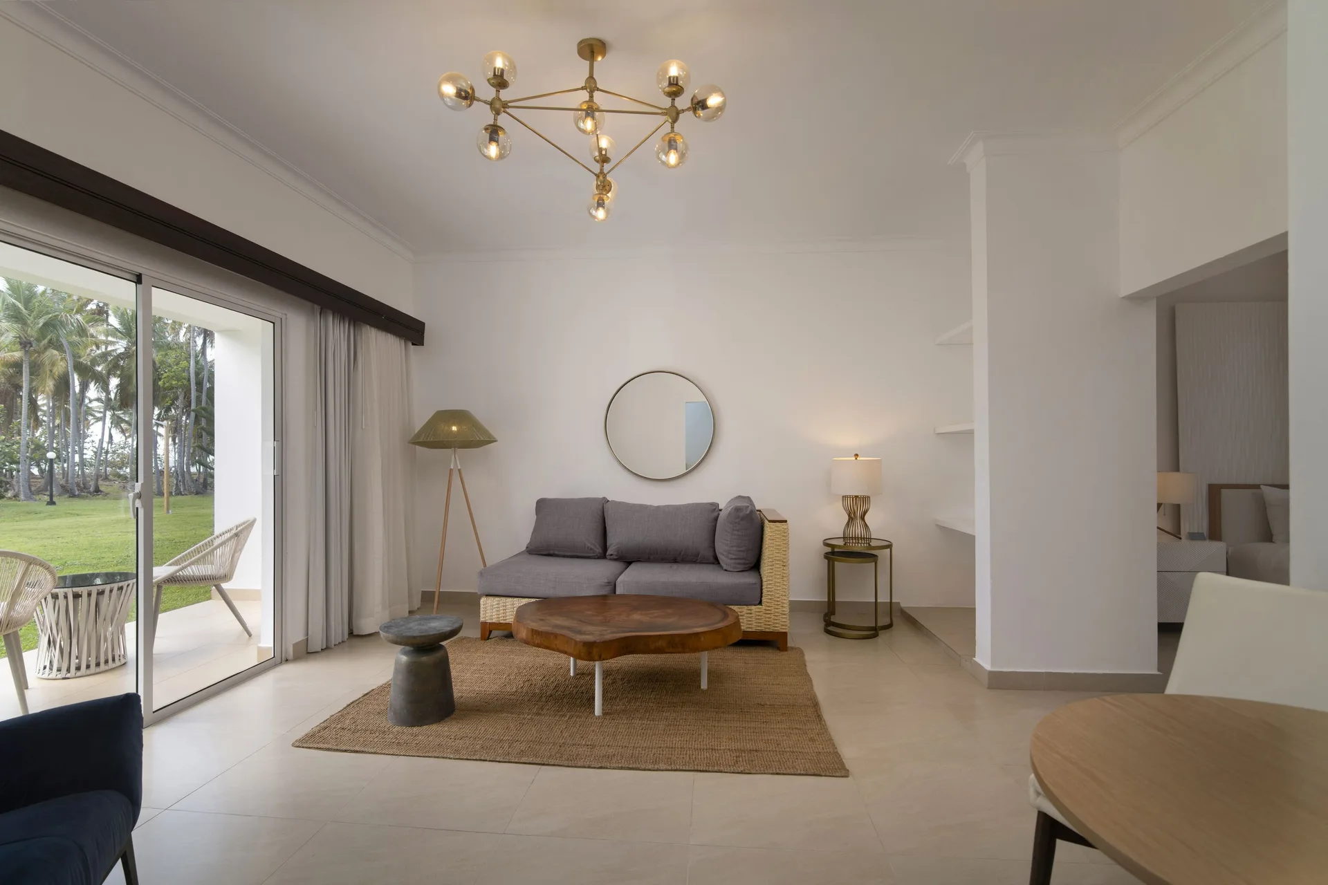 Suite living area with sofa, round table, and patio doors at Wyndham Alltra Samana Resort.