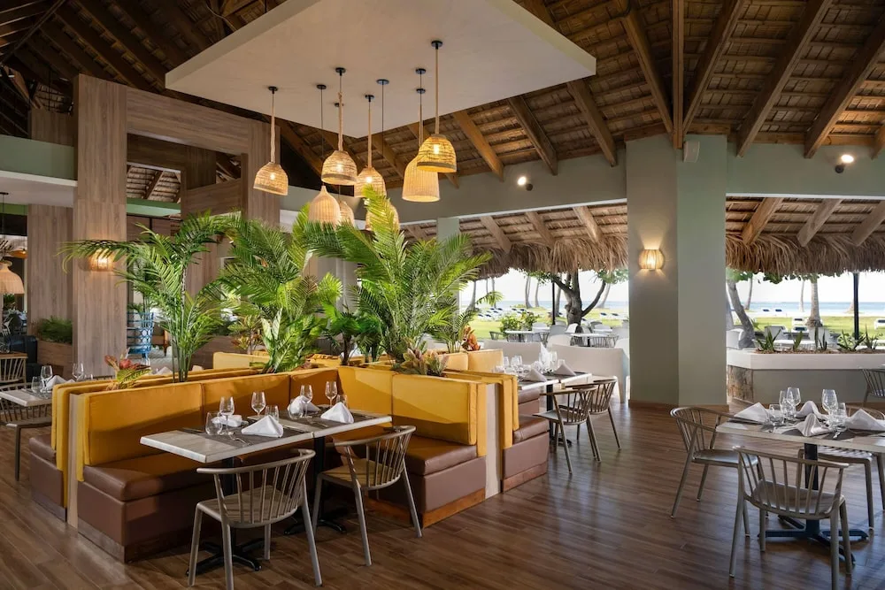 A beachfront restaurant dining room is set with tables at Wyndham Alltra Samana Resort.