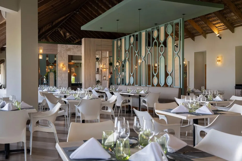 Bella dining room with set tables and white chairs at Wyndham Alltra Samana Resort.