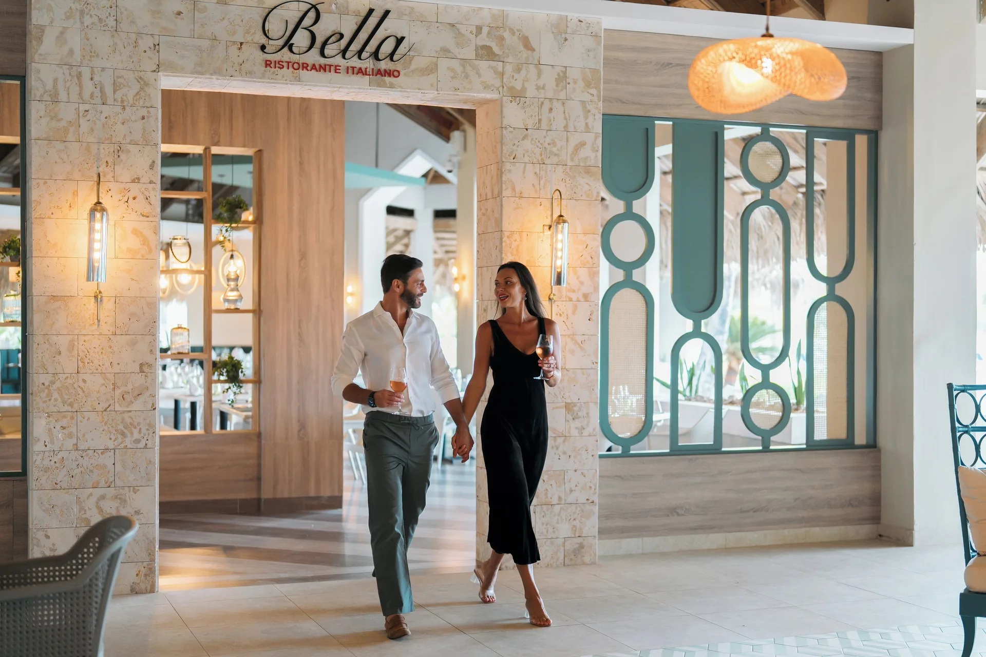 Bella restaurant entrance with guests holding drinks at Wyndham Alltra Samana Resort.